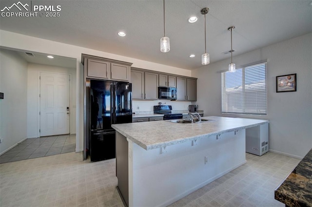 kitchen featuring sink, hanging light fixtures, light tile patterned floors, a center island with sink, and black appliances