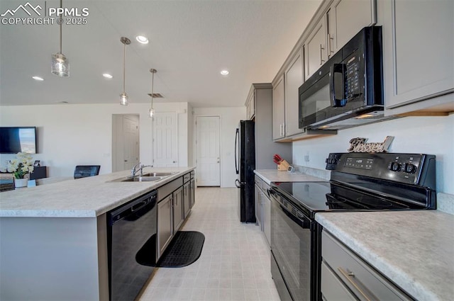 kitchen featuring sink, gray cabinetry, hanging light fixtures, black appliances, and an island with sink