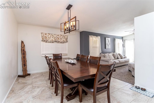 dining room with ceiling fan with notable chandelier and baseboards