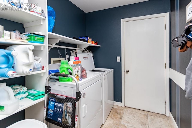 clothes washing area with light tile patterned floors, laundry area, washing machine and dryer, and baseboards