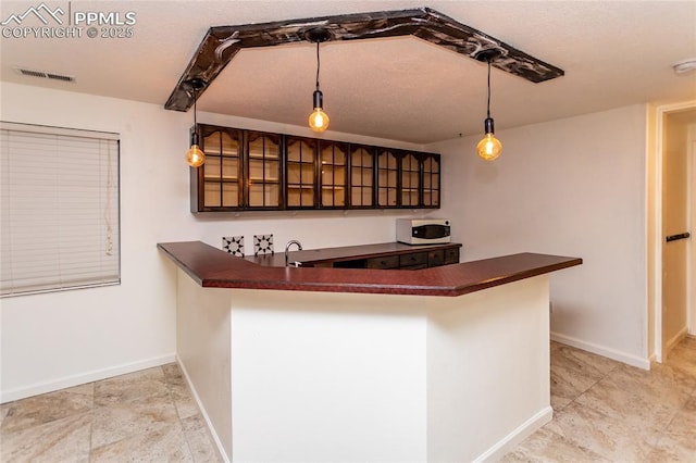 bar featuring hanging light fixtures, white microwave, visible vents, and baseboards