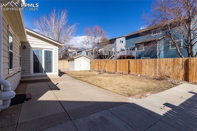 view of patio featuring a storage shed, an outdoor structure, fence, and a residential view