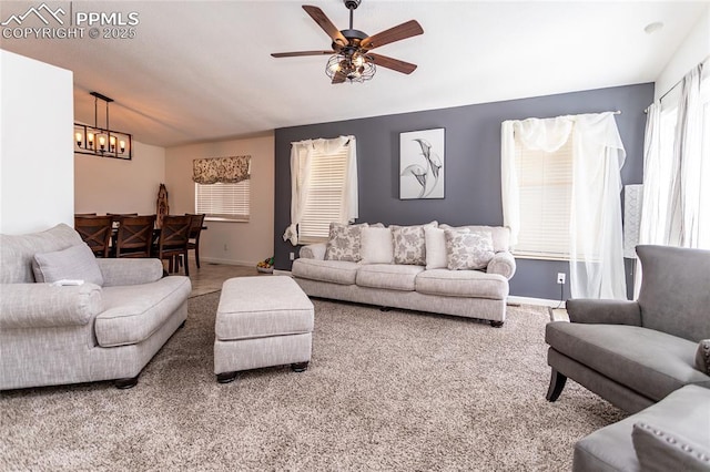 living room with carpet flooring, baseboards, and ceiling fan with notable chandelier