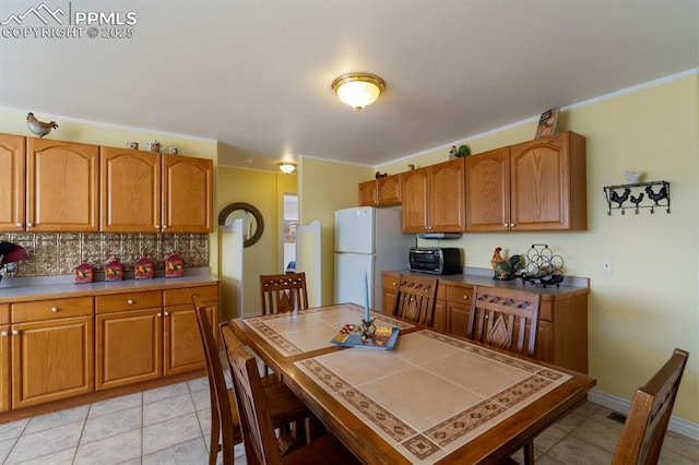 kitchen featuring tasteful backsplash, white fridge, and light tile patterned floors