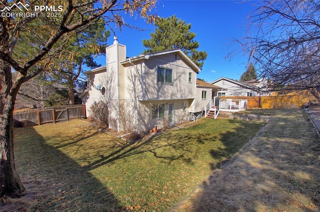 rear view of property with a wooden deck and a lawn