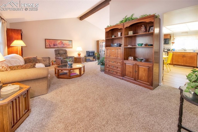 carpeted living room with sink and vaulted ceiling with beams