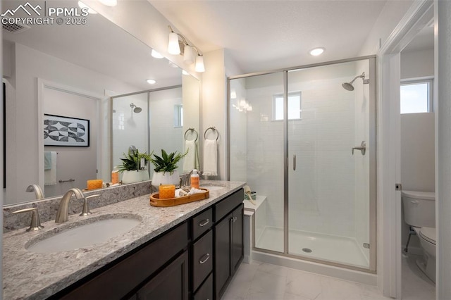 bathroom featuring a shower with door, vanity, and toilet