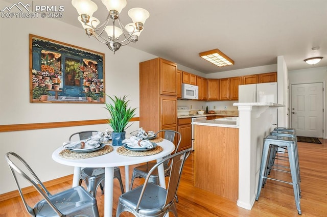 kitchen featuring hanging light fixtures, a center island, white appliances, and light wood-type flooring