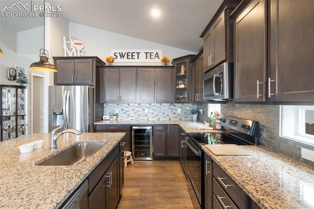 kitchen featuring wine cooler, sink, pendant lighting, stainless steel appliances, and light stone countertops