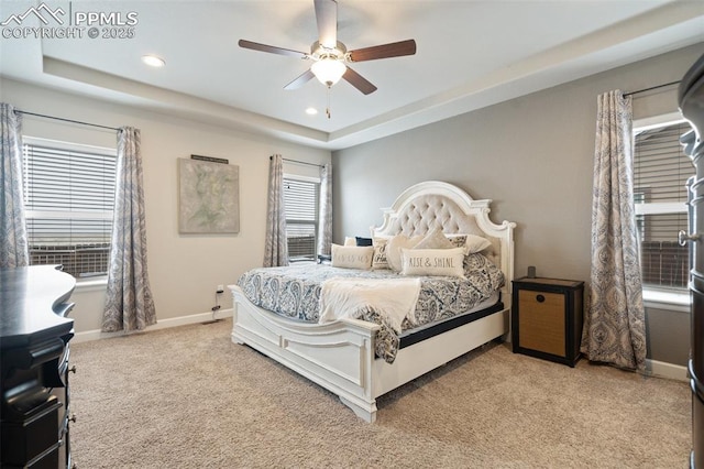 bedroom featuring light carpet, a raised ceiling, and ceiling fan