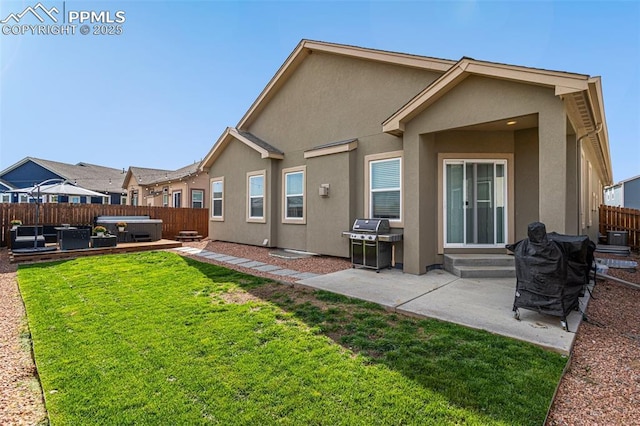 rear view of house featuring a yard, a hot tub, and a patio