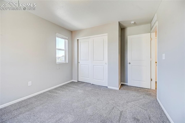 unfurnished bedroom with light colored carpet and a closet