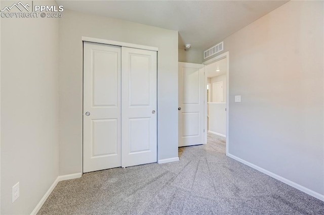 unfurnished bedroom featuring light carpet and a closet