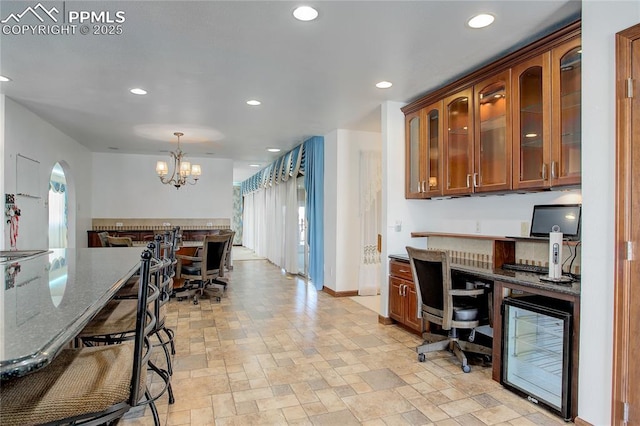 kitchen featuring pendant lighting, dark stone countertops, beverage cooler, and a chandelier