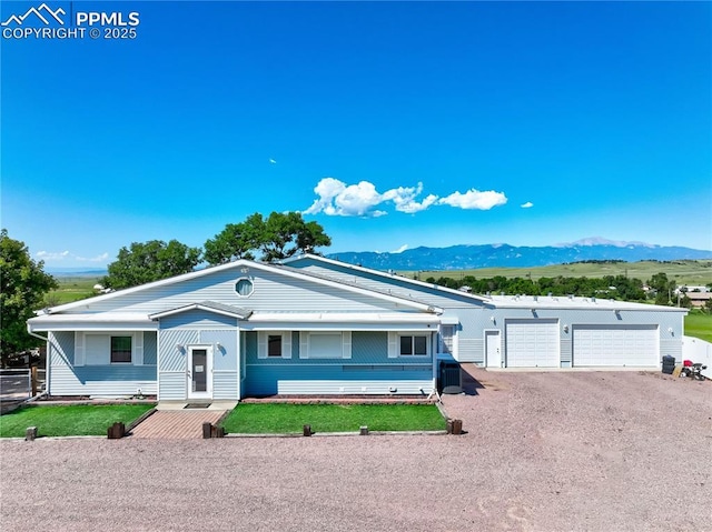 ranch-style home with a mountain view, a garage, and a front yard