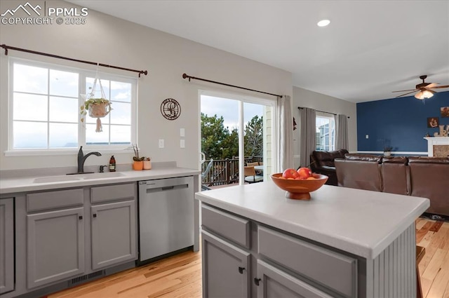 kitchen featuring gray cabinetry, sink, stainless steel dishwasher, and light hardwood / wood-style flooring