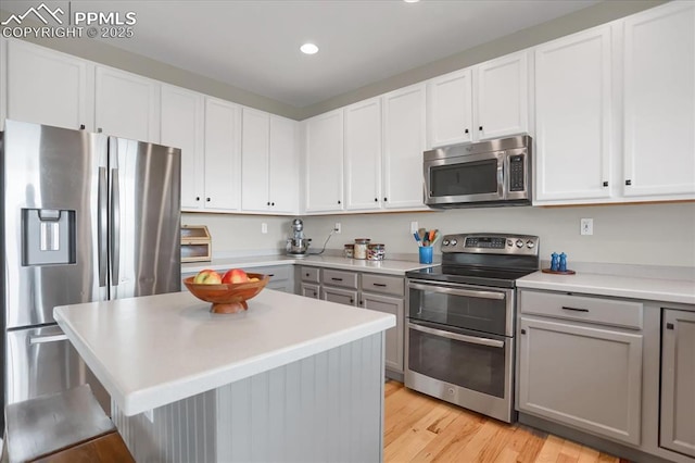 kitchen featuring white cabinetry, appliances with stainless steel finishes, gray cabinetry, and light hardwood / wood-style floors