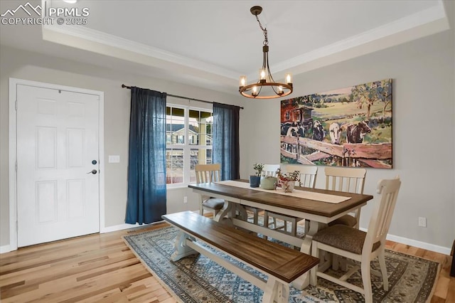 dining area featuring hardwood / wood-style floors, a tray ceiling, ornamental molding, and a chandelier