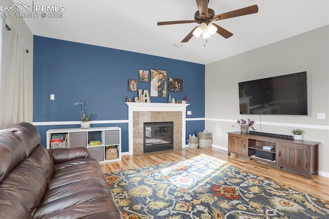 living room featuring ceiling fan, wood-type flooring, and a tile fireplace