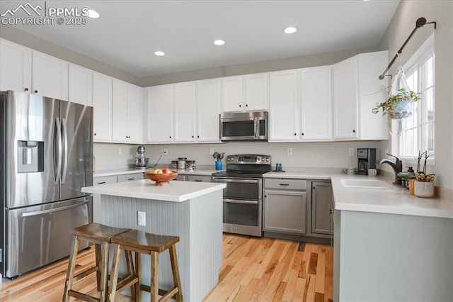 kitchen featuring sink, a center island, a kitchen breakfast bar, gray cabinets, and stainless steel appliances