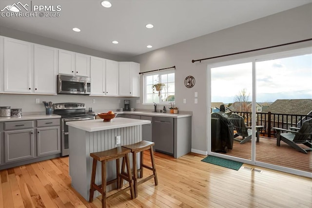 kitchen featuring sink, a breakfast bar area, gray cabinetry, stainless steel appliances, and a kitchen island