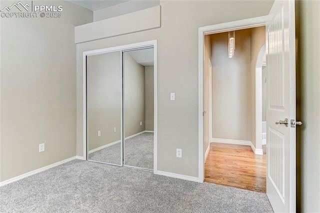 unfurnished bedroom featuring light carpet and a closet