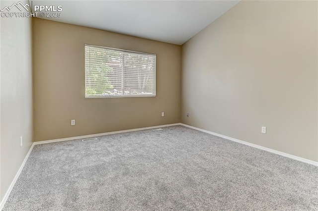 carpeted spare room featuring vaulted ceiling