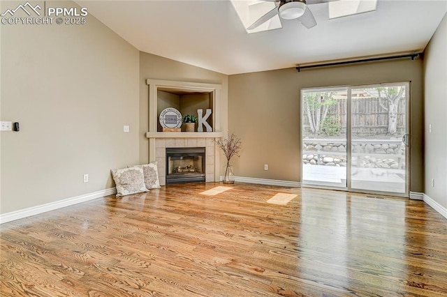 unfurnished living room with a tiled fireplace, vaulted ceiling, ceiling fan, and light wood-type flooring