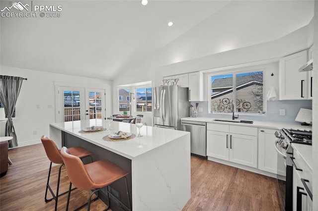 kitchen featuring appliances with stainless steel finishes, a center island, white cabinets, and a kitchen breakfast bar