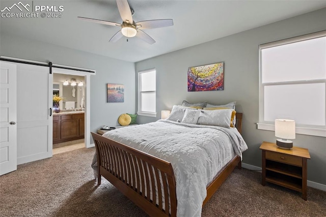 bedroom with a barn door, baseboards, ensuite bath, ceiling fan, and carpet