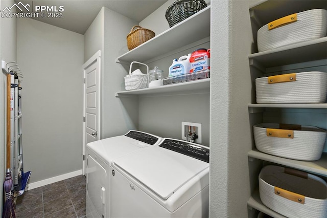 clothes washing area featuring laundry area, dark tile patterned floors, washing machine and clothes dryer, and baseboards