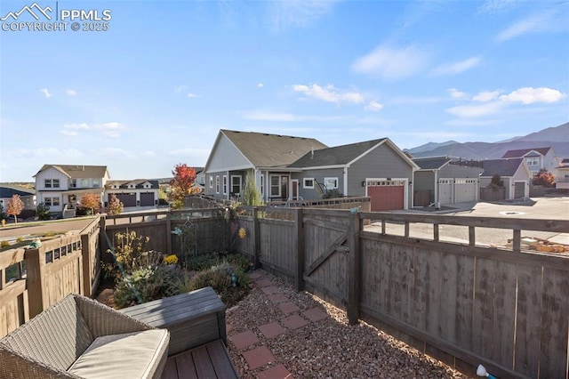 exterior space featuring a mountain view, a gate, a fenced backyard, and a residential view