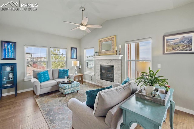 living area with vaulted ceiling, a fireplace, wood finished floors, and baseboards