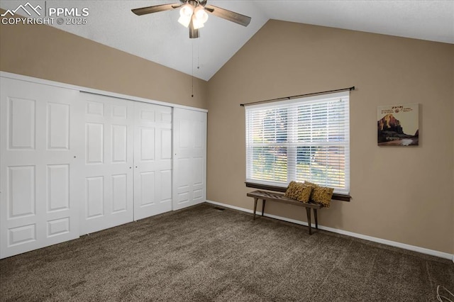 unfurnished bedroom featuring dark carpet, vaulted ceiling, a closet, and ceiling fan