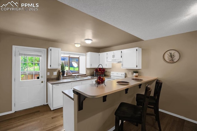 kitchen featuring white appliances, kitchen peninsula, light wood-type flooring, and white cabinets