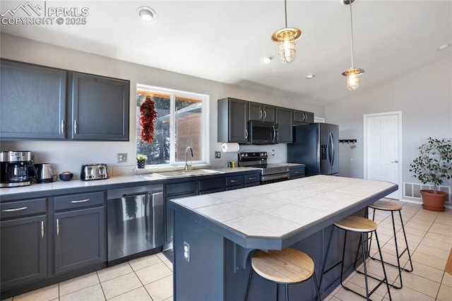 kitchen featuring a kitchen island, a kitchen breakfast bar, hanging light fixtures, stainless steel appliances, and a sink