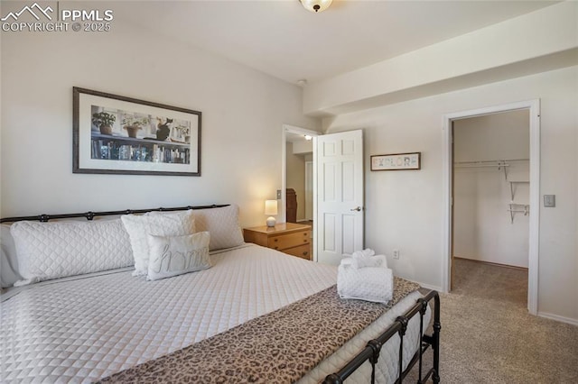 carpeted bedroom featuring a closet, a spacious closet, and baseboards