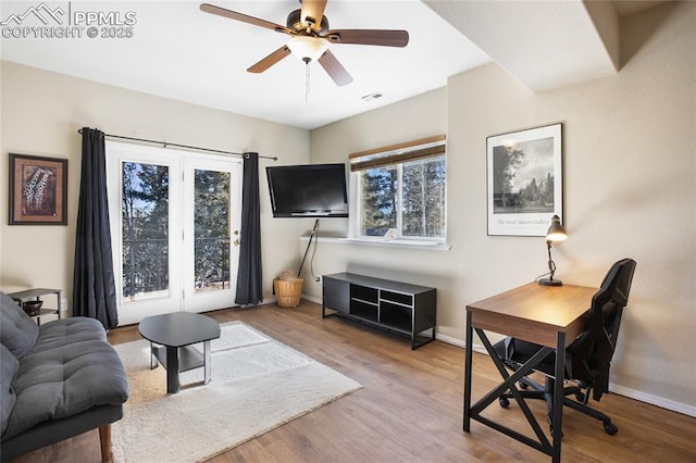 living room featuring a ceiling fan, visible vents, baseboards, and wood finished floors