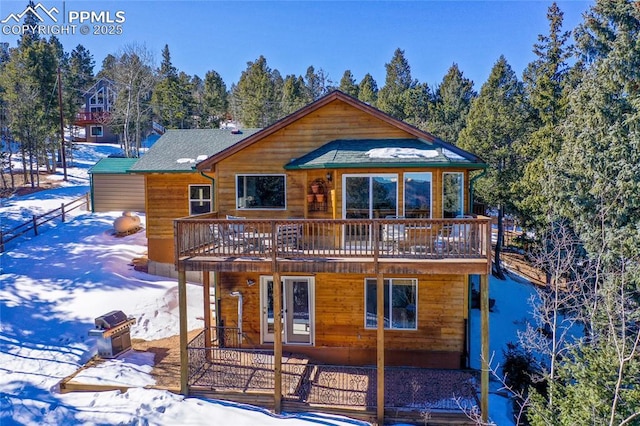 snow covered back of property featuring a wooden deck