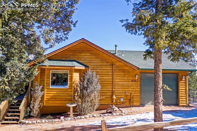 log cabin with a shingled roof, driveway, a garage, and stairs