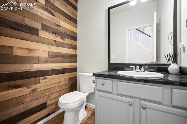 bathroom with vanity, tile patterned floors, toilet, and wood walls