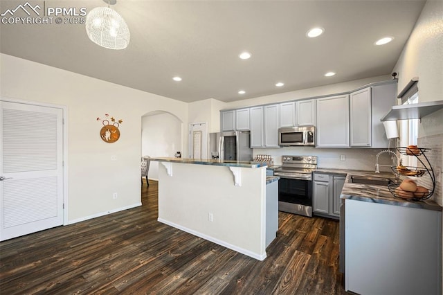 kitchen with appliances with stainless steel finishes, dark hardwood / wood-style floors, sink, gray cabinetry, and a center island