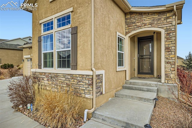 view of exterior entry with stone siding and stucco siding