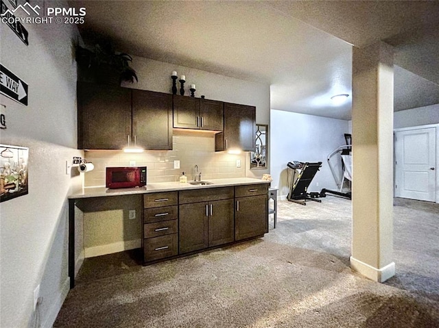 kitchen with sink, light colored carpet, backsplash, and dark brown cabinetry