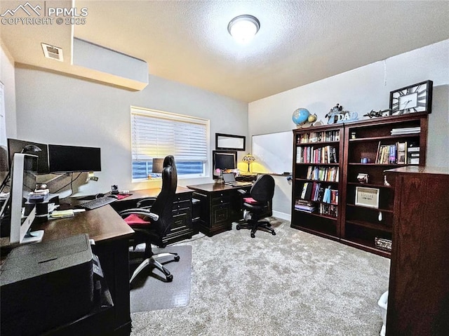 carpeted office featuring a textured ceiling