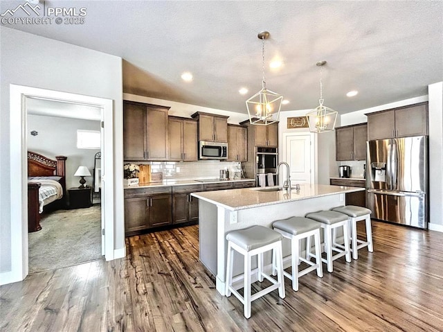 kitchen with pendant lighting, a breakfast bar area, stainless steel appliances, tasteful backsplash, and a center island with sink