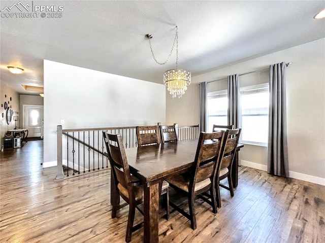 dining space featuring wood-type flooring and a notable chandelier