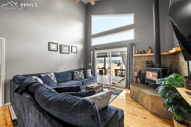 living room with light hardwood / wood-style flooring, a high ceiling, and a wood stove