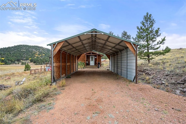 view of parking / parking lot featuring a carport, a mountain view, and a rural view