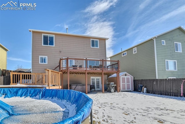 snow covered property with a swimming pool with hot tub and a storage shed